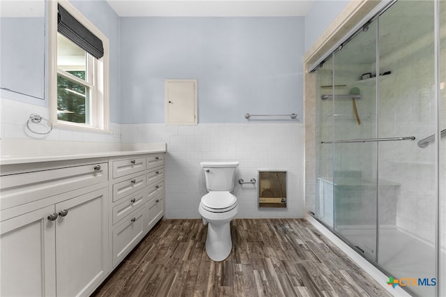 bathroom featuring walk in shower, toilet, hardwood / wood-style flooring, and tile walls