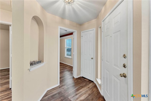 foyer entrance featuring dark wood-style flooring and baseboards