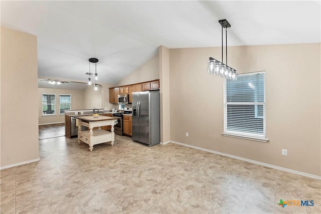 kitchen with lofted ceiling, stainless steel appliances, baseboards, brown cabinetry, and a center island with sink