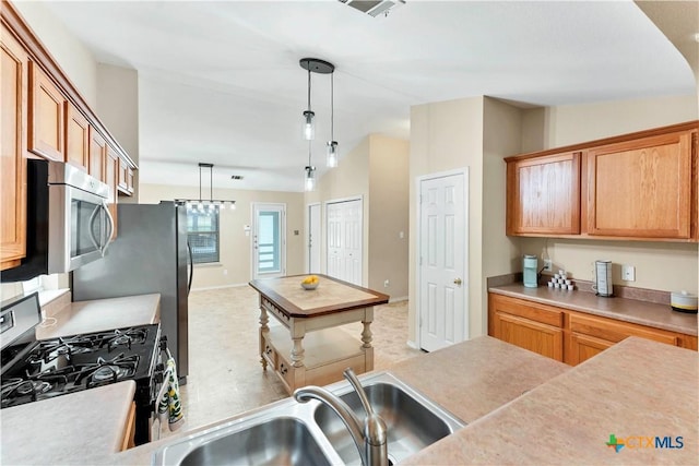 kitchen featuring lofted ceiling, hanging light fixtures, light countertops, stainless steel appliances, and a sink