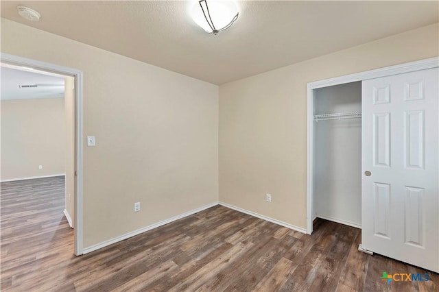 unfurnished bedroom with a closet, baseboards, and wood finished floors