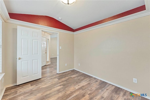 spare room with lofted ceiling, baseboards, and wood finished floors