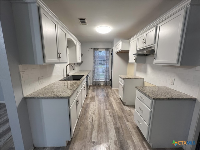 kitchen featuring dark stone countertops, hardwood / wood-style flooring, sink, and tasteful backsplash