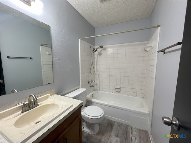 full bathroom featuring wood-type flooring, vanity, a textured ceiling, tiled shower / bath combo, and toilet