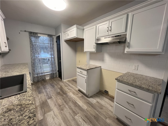 kitchen featuring white cabinetry, light stone counters, and hardwood / wood-style flooring