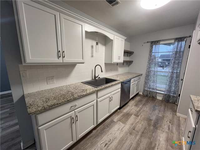 kitchen with sink, stainless steel dishwasher, light stone counters, dark wood-type flooring, and white cabinets