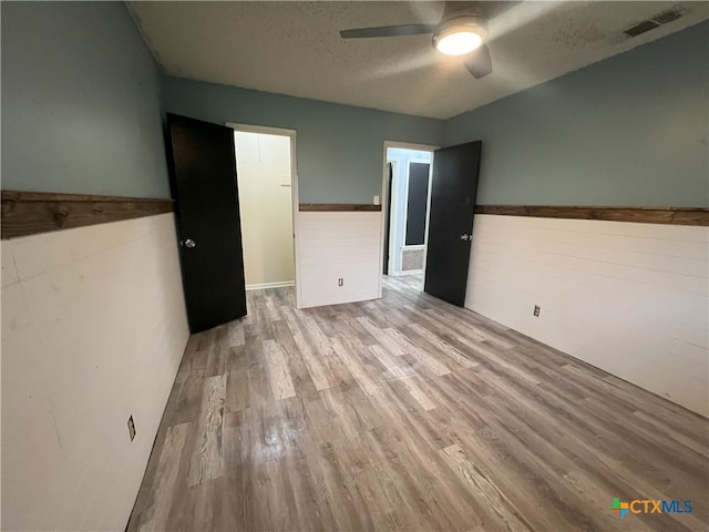 spare room with ceiling fan, light wood-type flooring, and a textured ceiling