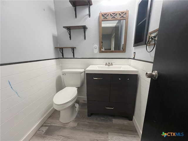 bathroom with toilet, vanity, and wood-type flooring