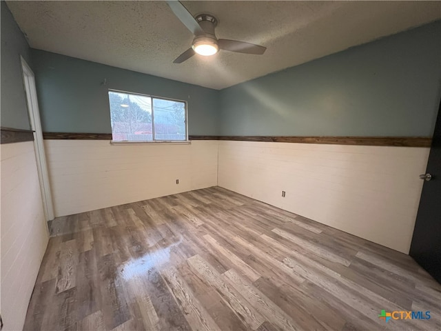 unfurnished room featuring ceiling fan, wood-type flooring, and a textured ceiling