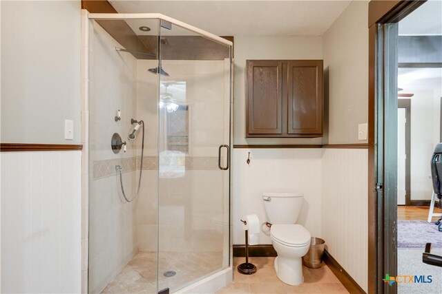 bathroom featuring tile patterned floors, toilet, and walk in shower