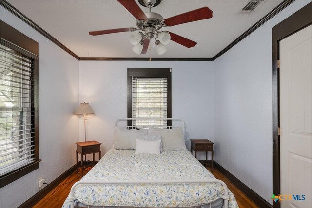 bedroom featuring ceiling fan, ornamental molding, and dark wood-type flooring