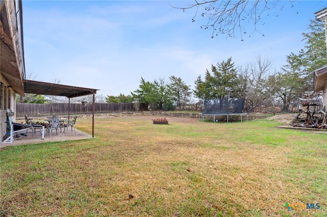 view of yard with a trampoline and a patio area