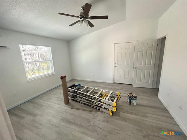 bedroom featuring an AC wall unit, ceiling fan, wood finished floors, and baseboards