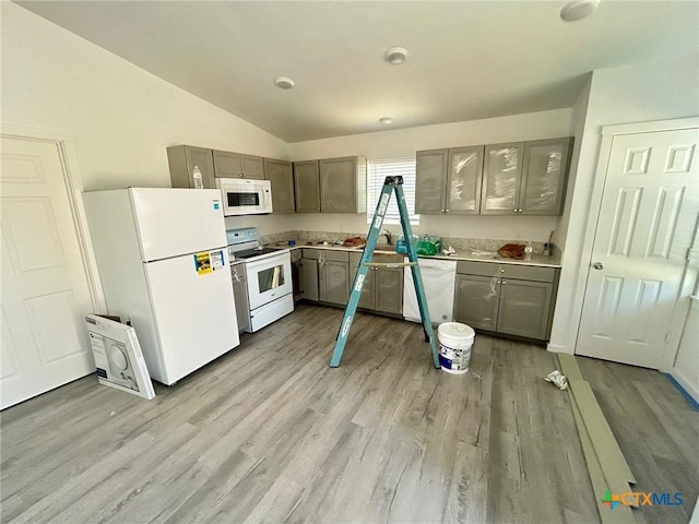 kitchen featuring gray cabinets, vaulted ceiling, and white appliances
