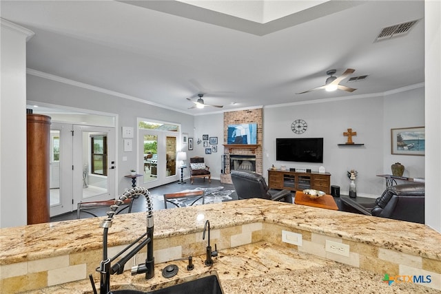 kitchen featuring a brick fireplace, sink, french doors, and ornamental molding