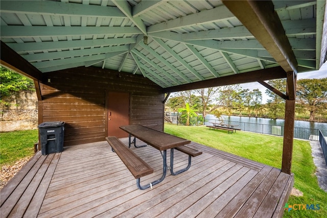 wooden terrace with a water view and a lawn