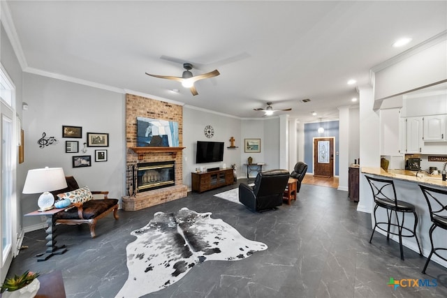 living room featuring a brick fireplace, ceiling fan, and crown molding