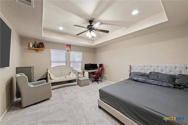 bedroom with ceiling fan, a tray ceiling, carpet, and a textured ceiling