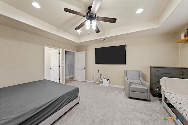 carpeted bedroom with a raised ceiling and ceiling fan