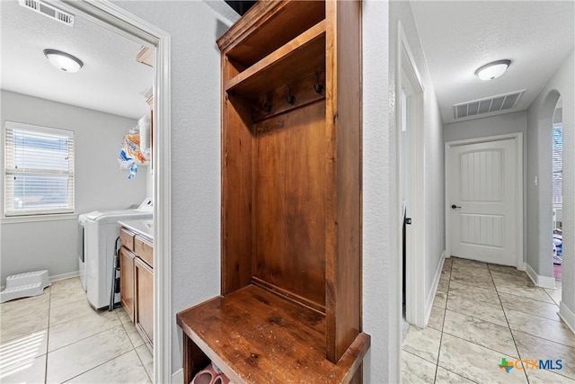 mudroom featuring independent washer and dryer, a textured ceiling, and light tile patterned flooring