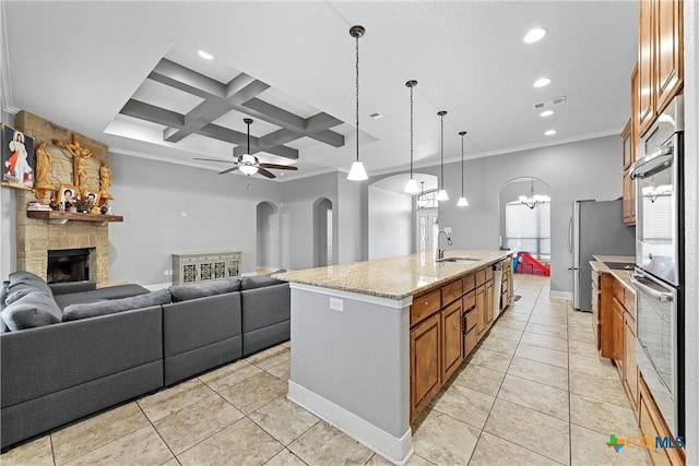 kitchen featuring coffered ceiling, a stone fireplace, ornamental molding, pendant lighting, and a large island