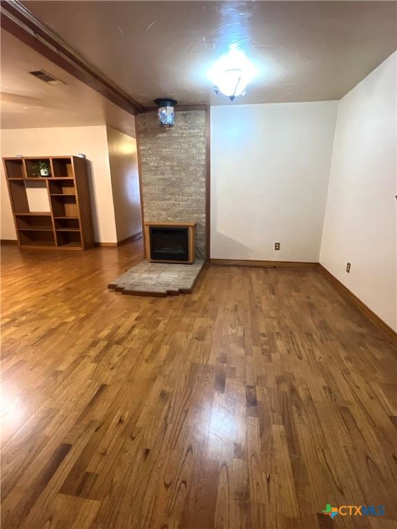 6769 Cedar Cove Rd, Belton, TX 76513 - unfurnished living room featuring wood finished floors, a stone fireplace, and baseboards