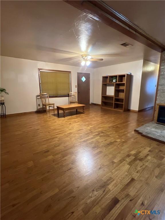 6769 Cedar Cove Rd, Belton, TX 76513 - unfurnished living room featuring wood finished floors, a ceiling fan, baseboards, and a stone fireplace