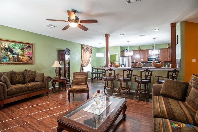 living room with visible vents, baseboards, decorative columns, a ceiling fan, and dark wood-style flooring