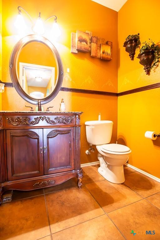 bathroom with tile patterned flooring, toilet, vanity, and baseboards