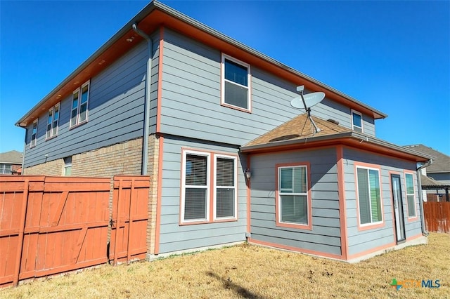 rear view of property with a yard and fence