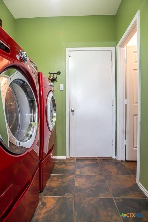 clothes washing area with stone finish flooring, baseboards, washing machine and dryer, and laundry area