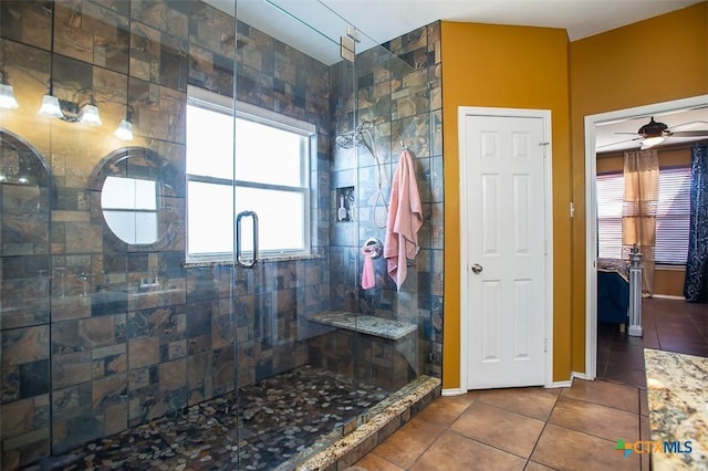 bathroom featuring tile patterned floors, a ceiling fan, a stall shower, and baseboards