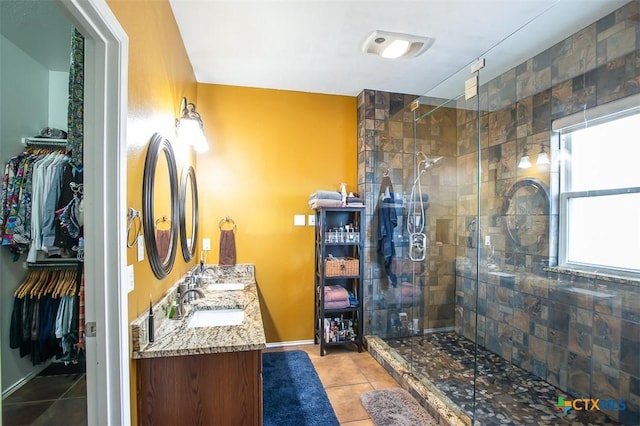 bathroom featuring tile patterned floors, a shower stall, a walk in closet, and a sink