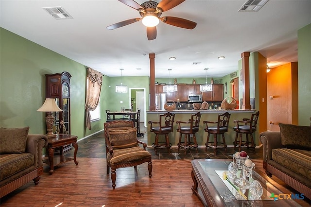 living room featuring visible vents, baseboards, dark wood-type flooring, and a ceiling fan