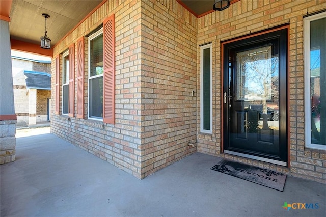 entrance to property featuring brick siding and a porch