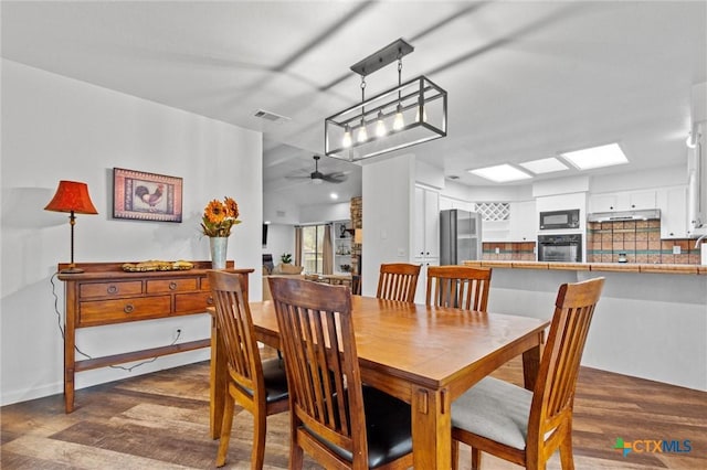 dining room featuring dark wood-type flooring, a skylight, and ceiling fan