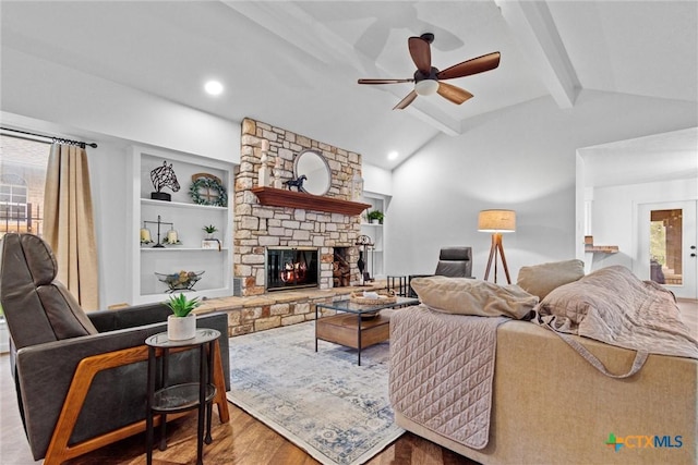 living room featuring built in features, a fireplace, lofted ceiling with beams, ceiling fan, and light hardwood / wood-style floors