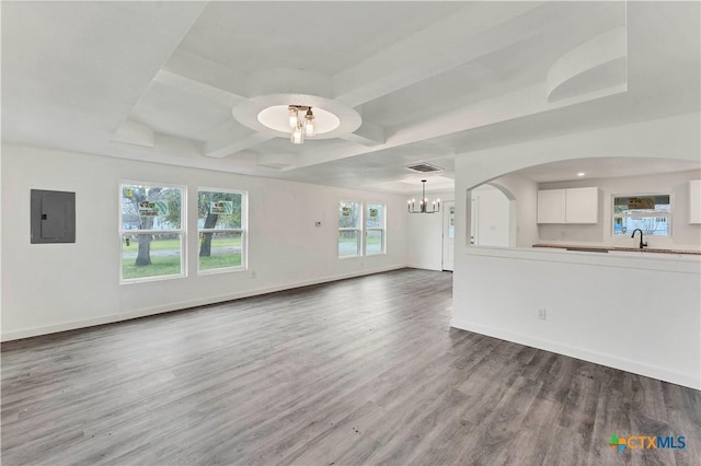 414 Ellis St, Seguin, TX 78155 - unfurnished living room with electric panel, baseboards, wood finished floors, a sink, and an inviting chandelier