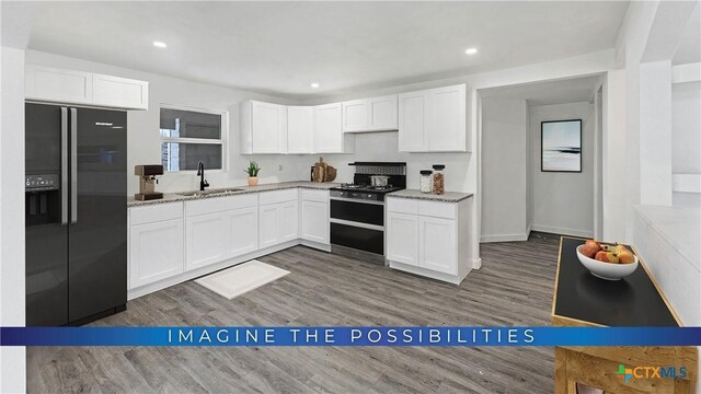 414 Ellis St, Seguin, TX 78155 - kitchen featuring black range, refrigerator with ice dispenser, a sink, white cabinets, and wood finished floors
