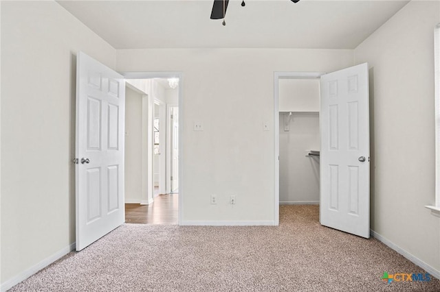 unfurnished bedroom with ceiling fan, a walk in closet, a closet, and carpet floors