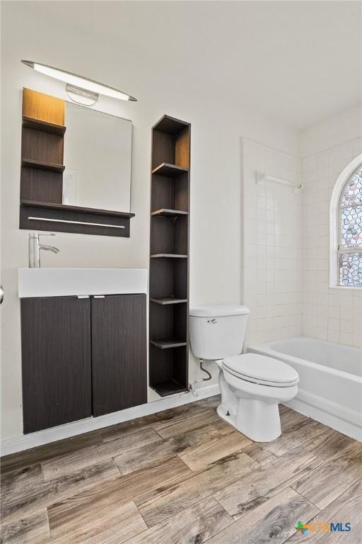 full bathroom featuring tiled shower / bath, vanity, and toilet