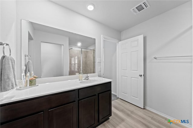 bathroom featuring wood-type flooring, an enclosed shower, and vanity