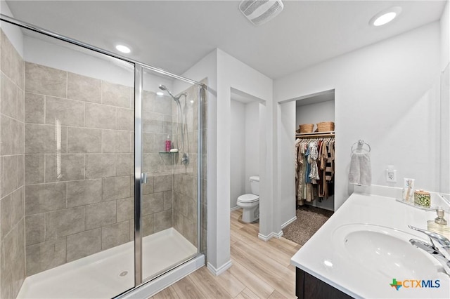 bathroom with hardwood / wood-style flooring, toilet, vanity, and a shower with shower door