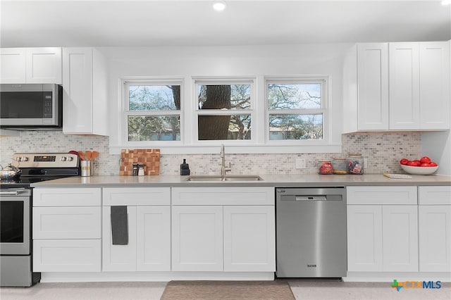 kitchen with white cabinets, decorative backsplash, sink, and appliances with stainless steel finishes