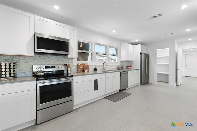 kitchen with backsplash, sink, white cabinets, and stainless steel appliances