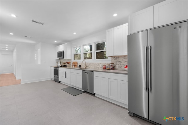 kitchen featuring decorative backsplash, white cabinetry, sink, and appliances with stainless steel finishes