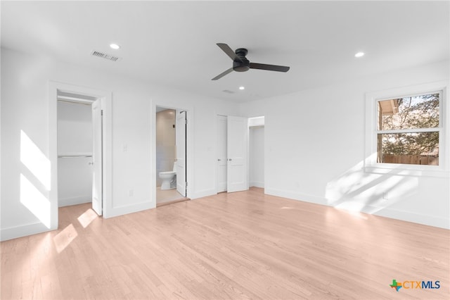 unfurnished bedroom with connected bathroom, ceiling fan, light hardwood / wood-style flooring, and a walk in closet