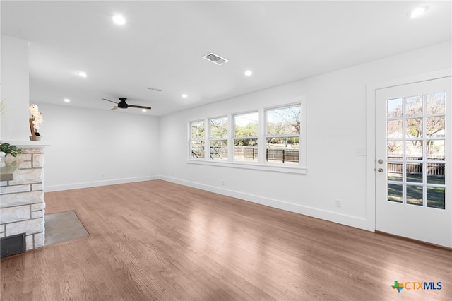 unfurnished living room featuring ceiling fan, light hardwood / wood-style floors, a healthy amount of sunlight, and a fireplace