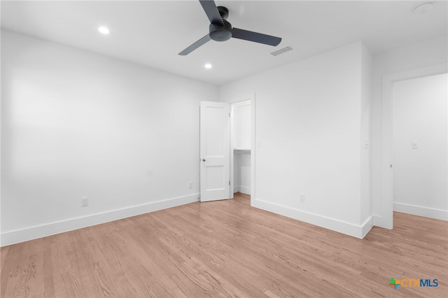 unfurnished bedroom featuring ceiling fan, a closet, a spacious closet, and light wood-type flooring