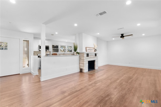 unfurnished living room featuring ceiling fan, a fireplace, and light hardwood / wood-style flooring